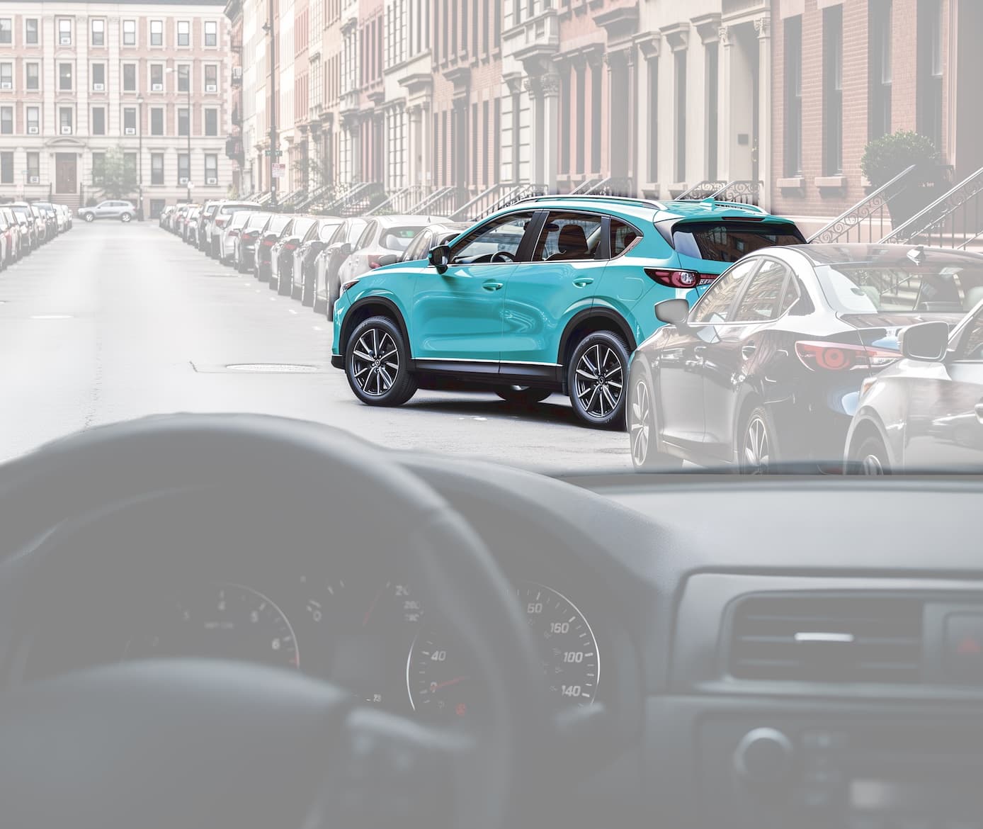 Teal SUV pulling out of a parallel parking space on a city street, seen from inside a car